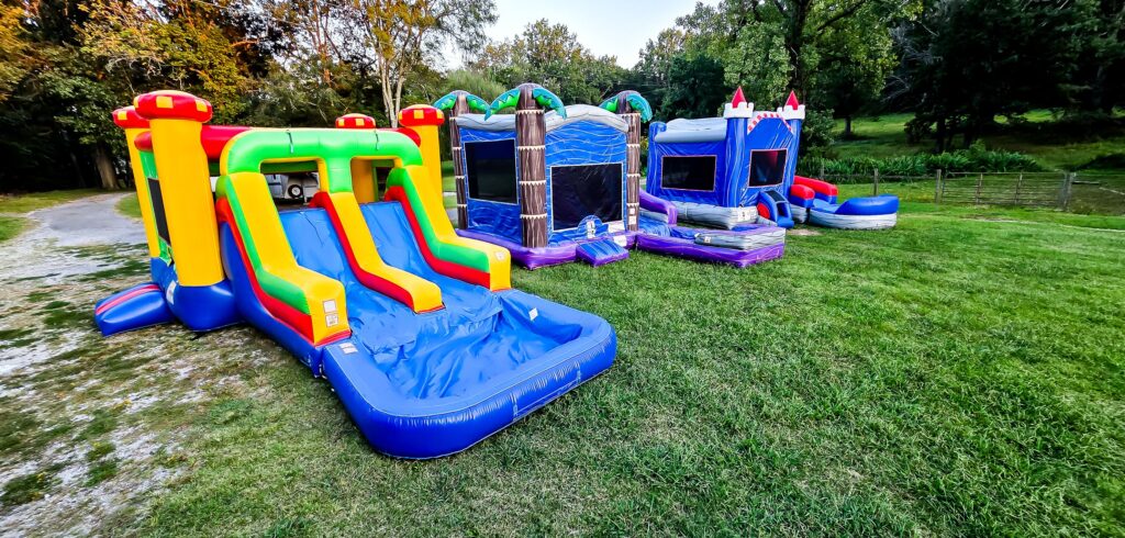 Colorful inflatable bounce house combos with slides set up on green grass, available for rent in Spring Hill, TN